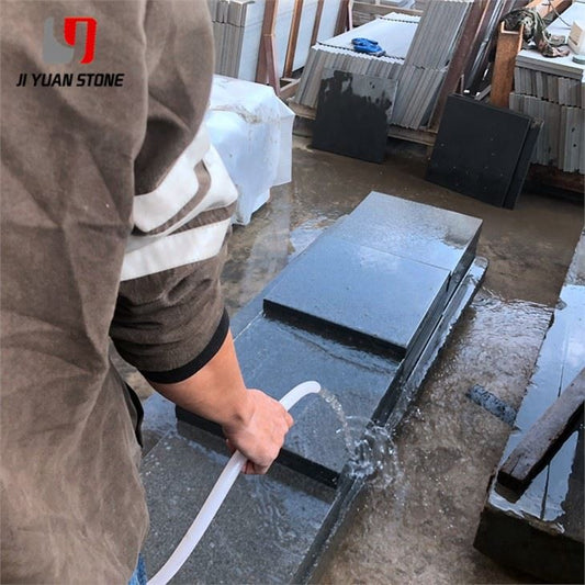 Worker measuring dark grey flamed granite steps at the Ji Yuan Stone factory