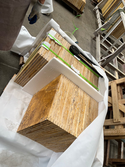 Packed golden travertine tile bundles with foam protection in wooden crate