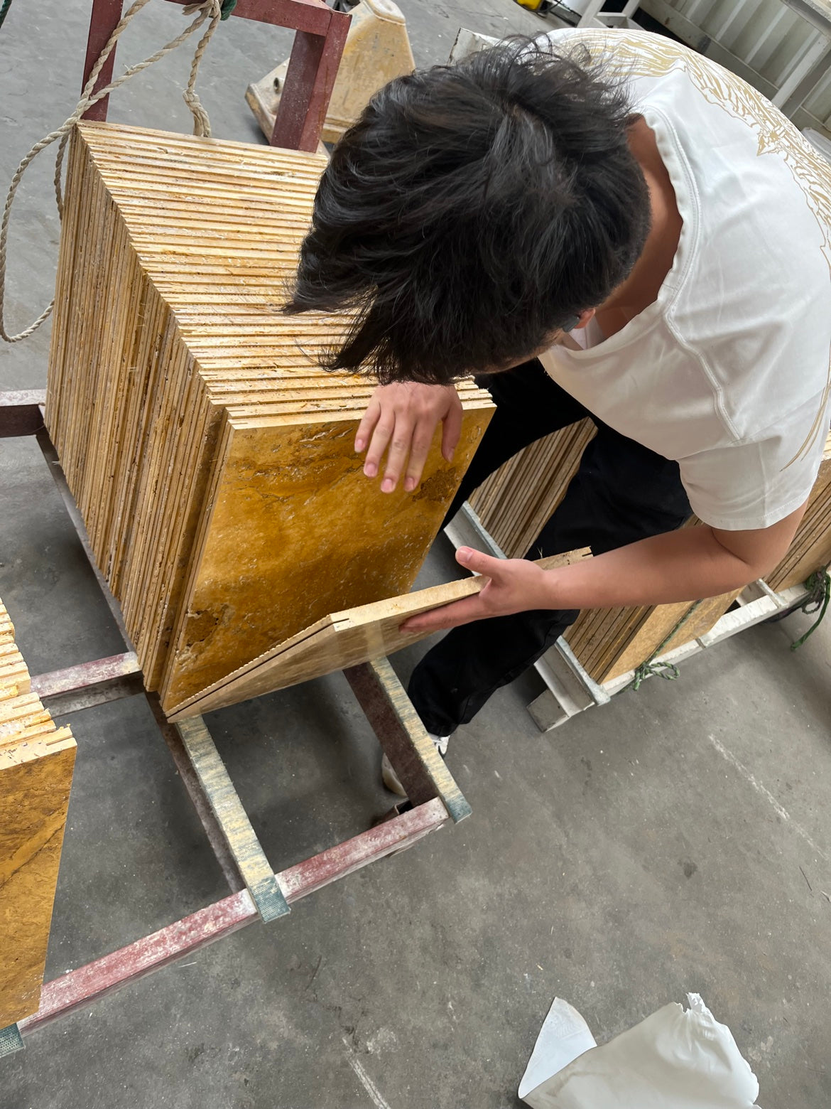 Worker inspecting golden travertine tiles piece by piece before packing