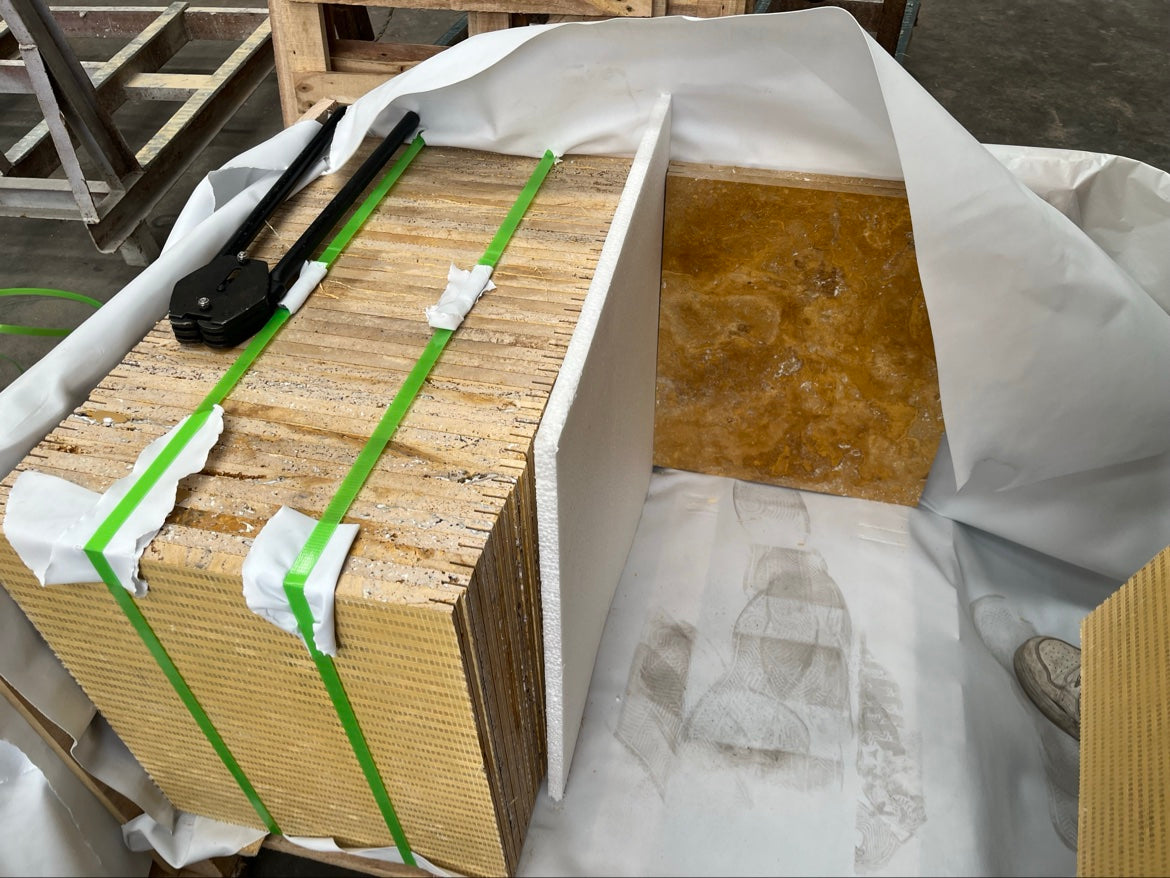 Golden travertine tiles being packed with foam separators and strapping
