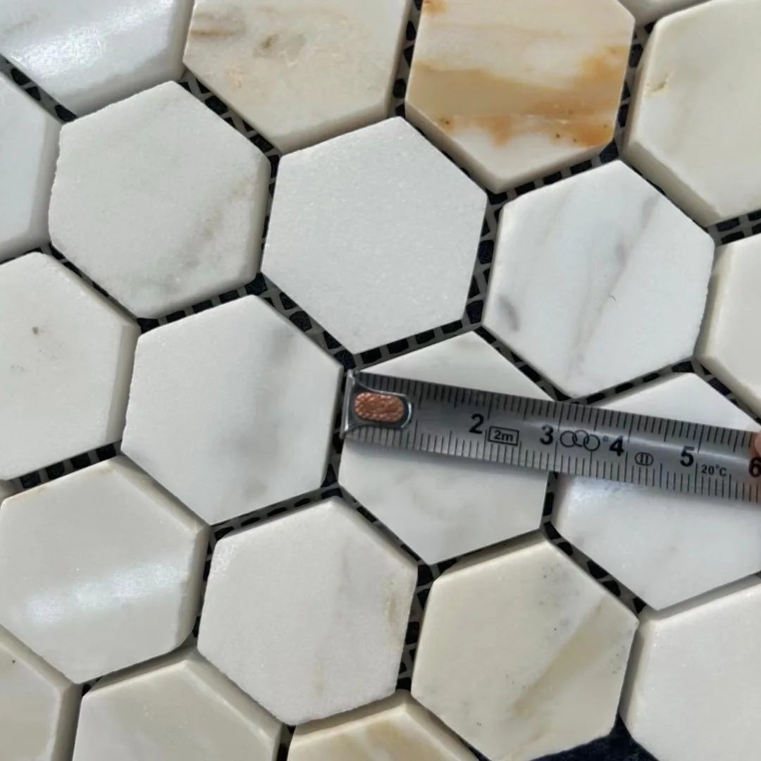Close-up of Calacatta Gold hexagon mosaic chips with a measuring tape